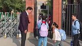 学校校长早上在校门口迎接学生，对孩子们一一回礼