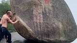 两名光着膀子的男子，在推动上山的大石头