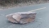 山坡岩石坠落在道路中央，路过司机用绞盘将岩石拖离马路