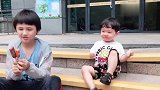 两个混血儿宝宝蹲在路边啃香肠,哥哥喂弟弟吃的样子好搞笑！