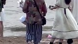 情侣在海边看海，奶奶上前送上一束花
