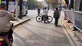男孩骑着共享电单车，载着自行车过马路