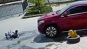 惊心一幕！男童玩滑板摔倒卷入轿车车底 安然无恙爬出