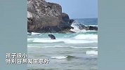 男子撑伞带娃在海浪中惊险玩耍，路人提醒却被无视：踩空就会卷走