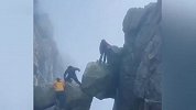 多名游客攀爬泰山仙人桥景点巨石，巨石相互抵撑下方悬空