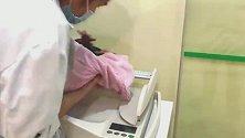 体重秤上的新生宝宝，一只小手从严密包裹里伸了出来，很有个性！