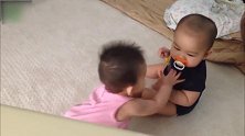黑衣宝宝在看镜头，粉衣宝宝就把奶嘴抢跑了，真有意思！
