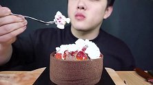 小哥吃一个巧克力草莓蛋糕，挤上一层奶油，吃得很满足