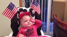萌娃头上戴着美国国旗，想要拿到国旗却够不到，只能看着了！