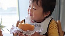 小宝宝第一次吃汉堡包，撅着小嘴一口一口的吃，还跟妈妈说真好吃