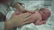 医生给新生儿做抚触按摩，宝宝舒服的趴在小床上