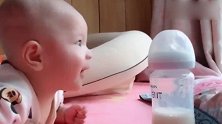 小宝宝一直盯着自己的奶瓶看，小眼神瞅来瞅去的，这是还没吃饱吗