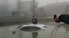 小伙子开车玩手机，把车开进水溏里，坐车顶淡定玩手机。