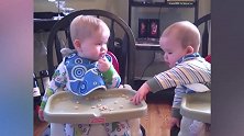 双胞胎宝宝在餐椅里吃零食，贪吃的弟弟吃完了抢哥哥的，好可爱啊
