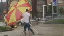 河南新乡：道路积水小伙冒雨打开窨井，还站一旁默默守护