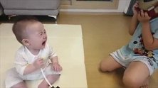 小宝宝原本自己玩得开开心心，结果被哥哥吓到大哭