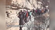 多名驴友无防护攀爬北京一悬崖峭壁，一女驴友单手扶山体，一手冲镜头挥动，村镇：属未开发区域，将加强劝导