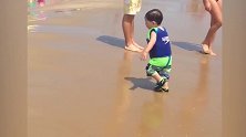 宝宝在海边，被一个大浪冲倒了，赶紧跑上岸边！