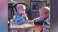 双胞胎宝宝在餐椅里吃零食，弟弟自己的吃完再吃哥哥的好可爱