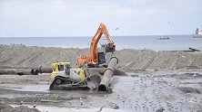 海边铺设排水管，一台大型挖掘机和一台推土机就搞定！