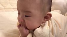 小宝宝独自一人趴床上，自顾自地吃着小手，可爱到爆棚！