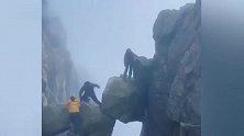 多名游客攀爬泰山仙人桥景点巨石，巨石相互抵撑下方悬空