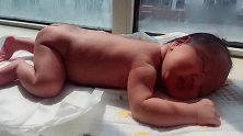 一个月大的小宝宝衣服都没穿，就趴在阳台上晒太阳