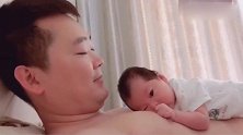 小宝宝趴在爸爸的胸前，呆呆的看着爸爸的模样真可爱