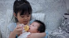 好有爱的姐妹俩，姐姐给宝宝喂水的样子好认真，温馨的画面好暖心