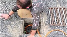 狗狗被困排污管道，但营救困难，人们直接砸开路面