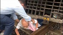 印度：一辆火车紧急刹车，人们从车底救出穿越铁轨的老人
