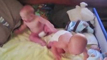 双胞胎小胖娃在床上玩耍，两团小胖肉直接滚成了一团，简直萌翻了