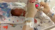 妈妈在保温箱里给早产儿换尿布，宝宝不时发出哀鸣声，听得人心痛