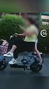太危险，山东一女子跷二郎腿单手骑车看手机，女儿伏背单腿独立。