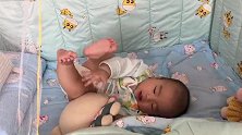 小宝宝躺在床上玩玩具，小腿翘得真高，小模样好萌啊！