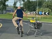 英国：男子一只手骑自行车一只手拉手推车运送物品不慎“翻车”