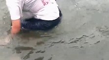 美女正在往水中走，不小心掉进了水坑里。