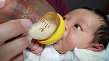 好萌！初生婴儿第一次用奶瓶喝奶，小拳头握得紧紧的，可认真了